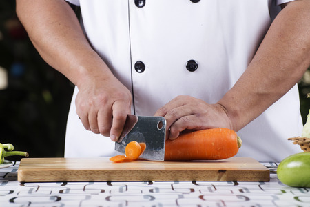 Chef cutting carrot on the wooden broadの写真素材
