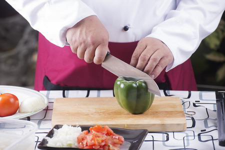 Chef cutting green bell pepper with knife before cooking / cooking spaghetti conceptの写真素材