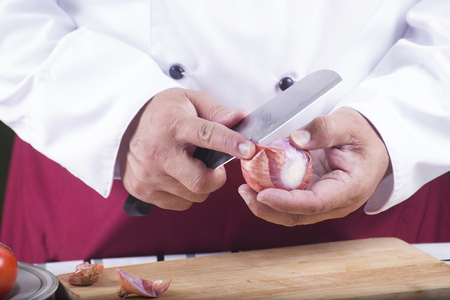 Chef peeling red onion with knife / cooking spagetti conceptの写真素材