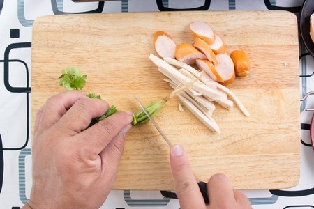 Chef chops coriander with knife beside slice of sausage / Cooking egg pan conceptの写真素材