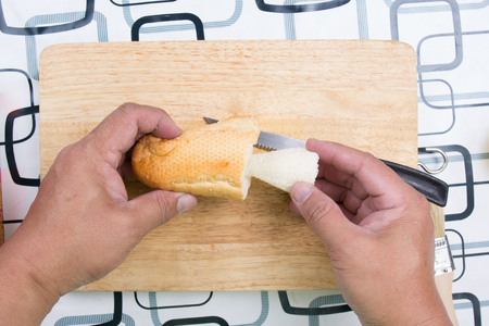 Hand with knife penetrate bread / cooking sausage bread conceptの写真素材