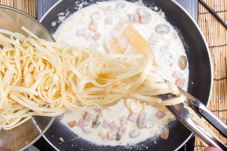Chef putting Spaghetti carbonara to pan with tongs / cooking spaghetti conceptの写真素材
