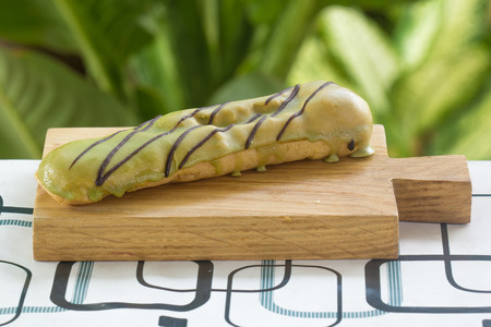 Green Tea coating Eclair on the wooden plate