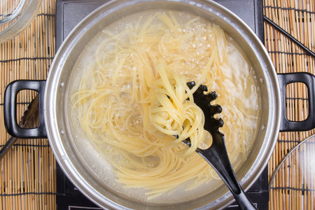 Spaghetti boiling in pan on electric stove / cooking spicy spaghetti conceptの写真素材
