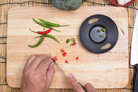 Hand cutting Hot Chili Peppers on wooden broad / cooking spicy spaghetti conceptの写真素材