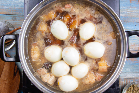 Chef putting boiled eggs for cooking streaky pork in pot / Cooking sweet brown Stewed pork gravy (Moo Pa-lo) conceptの写真素材
