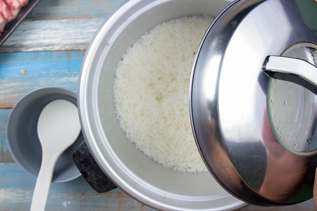 Chef open lip of electric rice cooker that cooking rice in homeの写真素材