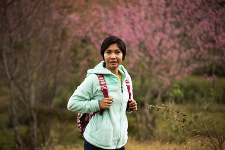 Asian woman stand among Pink flower King of tigers . Sakura , Cherry Blossoms grows in the mountains backgroundの写真素材