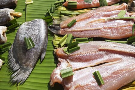 Set of sun dried gourami fish on Banana leaf / Salted gourami fish for Thai food preservationの写真素材