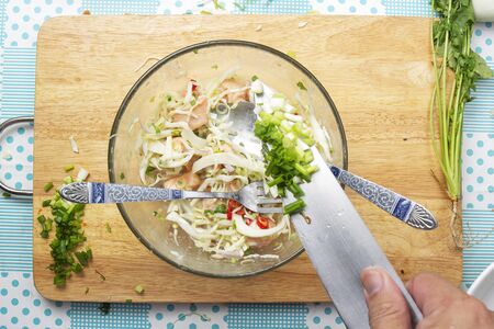 Chef cooking salmon salad with vegetable and herb to the bowl / Cooking Thai spicy salmon salad...