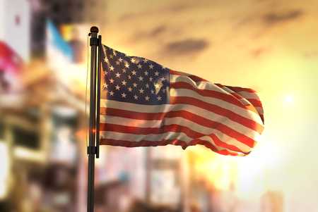 American Flag Against City Blurred Background At Sunrise Backlightの写真素材