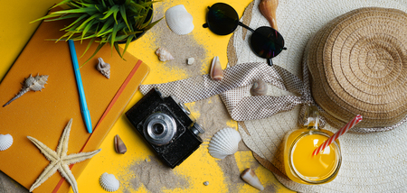 Summer Beach Accessories on Yellow Background. Camera, Starfish, Sunglasses, Sea Shell, Orange Juice and Sun Hat. Flat Lay Banner                 の写真素材