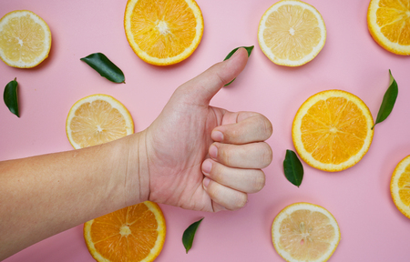 Thumb up on Orange Lemon Leaves Citrus Pattern on Pink Background Minimal Flat Layの写真素材