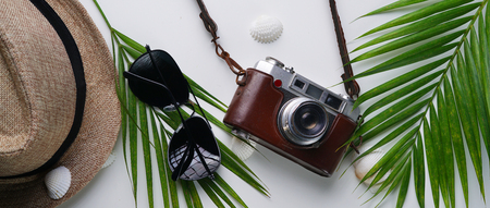 Sunglasses, Fedora Hat, Palm Leaf, Sea Shells and Vintage Camera. Flat Lay Traveling Holiday Vacation Banner Backgroundの写真素材