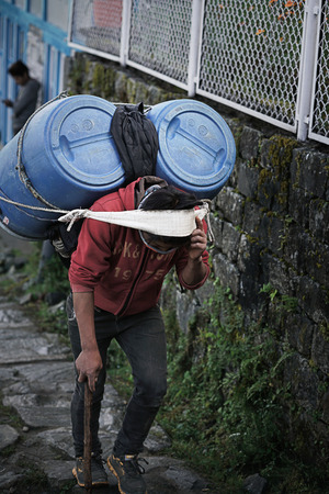 Man Carry Two Big Gallons on His Headon The Side of Tenzingâ€“Hillary Airport Runaway, Lukla...