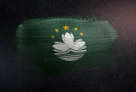 Macau Flag Made of Metallic Brush Paint on Grunge Dark Wallの写真素材