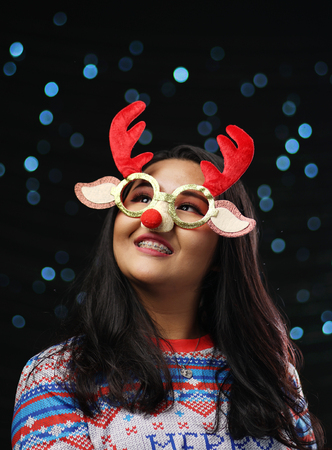 Asian Girl Wearing Christmas Sweater and Christmas Reindeer Glasses Red Nose. Looking Upの写真素材