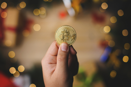 Hand Holding Bitcoin Above Christmas Decoration. Top Viewの写真素材