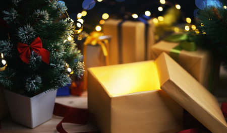 Open Christmas Box Gift Besides Small Christmas Tree. Glowing Lightの写真素材