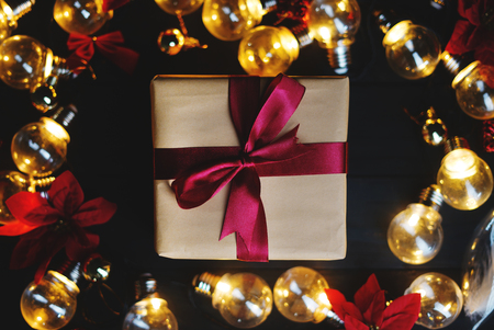 Christmas Gift Inside Light Bulbs and Red Poinsettia on Black Wood. Top Viewの写真素材