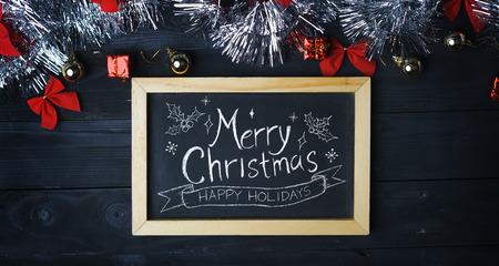 Merry Christmas Typography on Blackboard. Silver Christmas Ornament on Black Wood Plankの写真素材