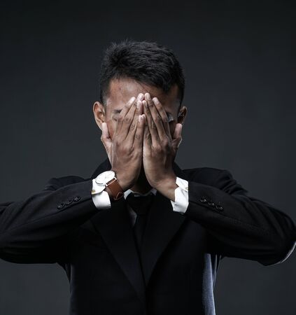 Desperate Businessman Covering Face. Losing Job Because World Recessionの写真素材