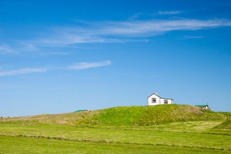 little house in iceland between a grenn meadow and the blue skyの写真素材