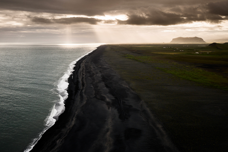 Sunset witz sunbeams at the southern coastline of Iceland seen from cape Dyrholaeyの写真素材