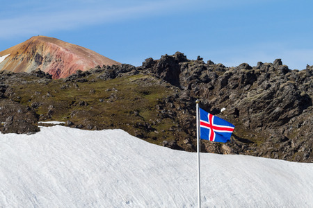 Flag of Iceland with lava, snow and a colorful mountain in Landmannalaugar in backgroundの写真素材