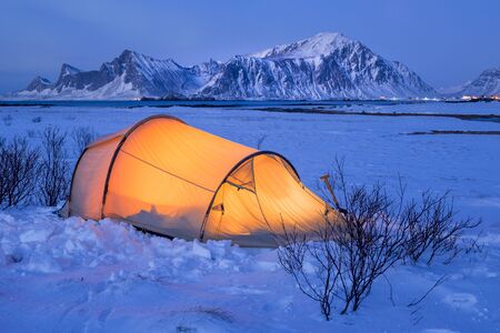 Illuminated tent at night on Lofoten islands in winterの写真素材