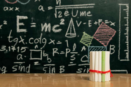 Going back to school concept with blackboard full of numbers and a busy student desk