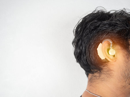 An asian man is wearing a hearing aid on white background. Space for text.の写真素材