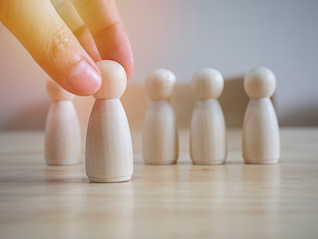 Hand choose a wooden figure to in front of line with each other figure and show different thinking ideas. Leadership and disruption for new normal concept.の写真素材