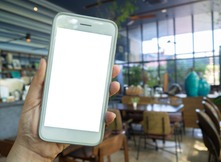 Mockup image of hand holding mobile phone with blank white screen vintage wood table in cafeの写真素材