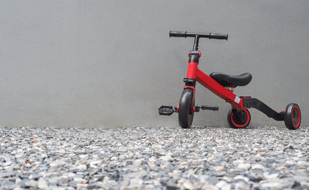 A red bike for children with cement wall behide at home. Mother teaching his son to ride a bike. Image for background of bike, activities at home.の写真素材