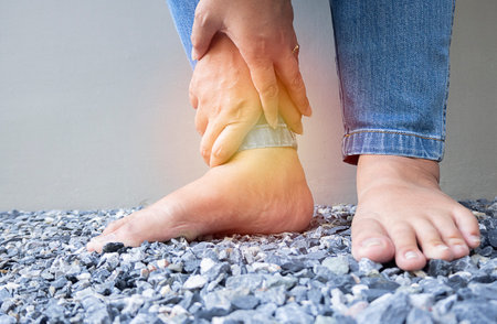 Close up of woman is standing  with spasm, cramp, sprained, dislocated ankle, ruptured tendon and joint pain. Health care and medical concept.の写真素材