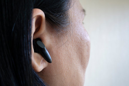 Close-up image of a young Asian woman put on wireless headphones. Smart accessories concept.
