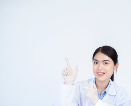 Young Asian woman working at scientist laboratory smiling and looking at the camera pointing with two hands and fingers to the side. Science, chemistry, biology, medicine and people concept.の写真素材