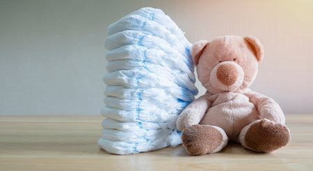 Stack of diapers for baby, toddler with toy teddy bear on table. set for boy girl for baby shower with copy space, banner.