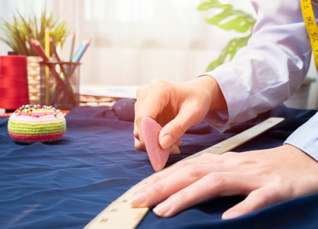Close up hands of woman tailor work with fabric on table in workshop studio. Creative clothes designer measure cloth for new collection in atelier. Busy female seamstress with textile. Dressmaker trendy creative spaceの写真素材