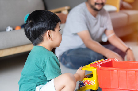 Asian Father and son are playing with toy car or truck and smiling while spending time together at home. Entertaining activity with kid at home conceptの写真素材