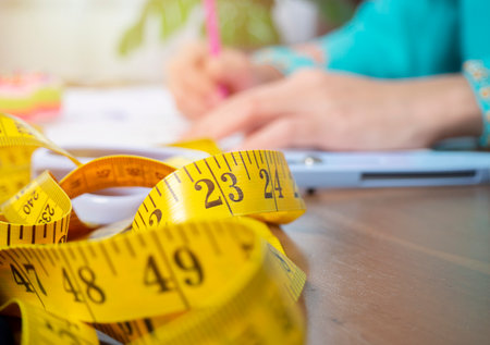 Selective focus. Muslim woman fashion designer measuring size of the dress with measurement tape in tailor shopの写真素材