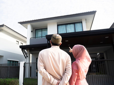 Homeowners. Back view of loving muslim couple pointing and looking at their dream house. Celebrating new purchase buying real estateの写真素材