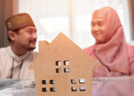 Selective focus. Muslim couple looking at each other and smiling , they are saving money to buy a new house.  Saving money and loan for construction real estate concept.の素材 [FY310202265925]