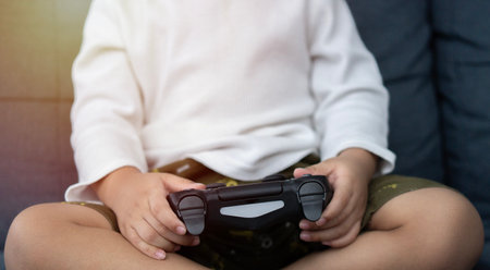 Technology and people concept . Cropped image of  boy with joystick playing video game at home.の写真素材