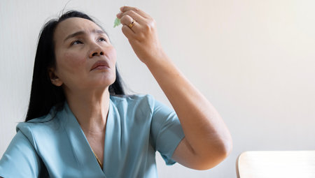 Portrait of Asian woman dripping her eye with medicinal drops natural tear. Disease of retina of eye. Conjunctivitis, keratitis, dry eye syndrome.の写真素材