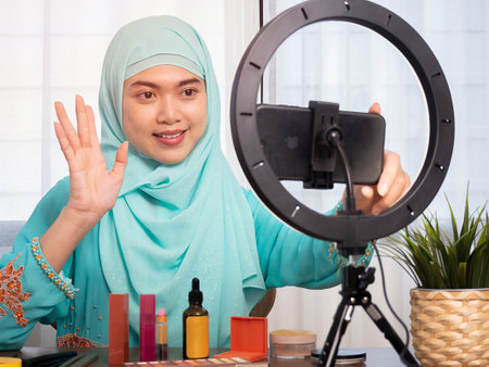 Beauty blogger woman filming daily make-up routine tutorial near camera. Influencer girl live streaming cosmetics product review.の写真素材
