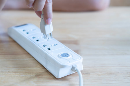 Closeup of a woman hand inserting a plug into electrical power strip. Electrician's professional equipmentの写真素材