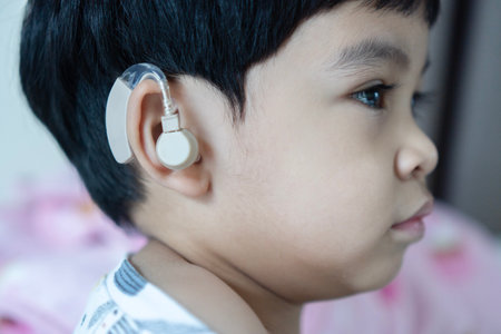 Asian child have a hearing aids with hearing problem. Hearing loss in childhood, symptoms and treatment concept. Close up, copy space.の写真素材