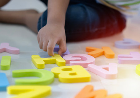 Selective focus. Toddler boy learning alphabet letter on the floor at home. Intellectual game preschool primary education concept.の写真素材